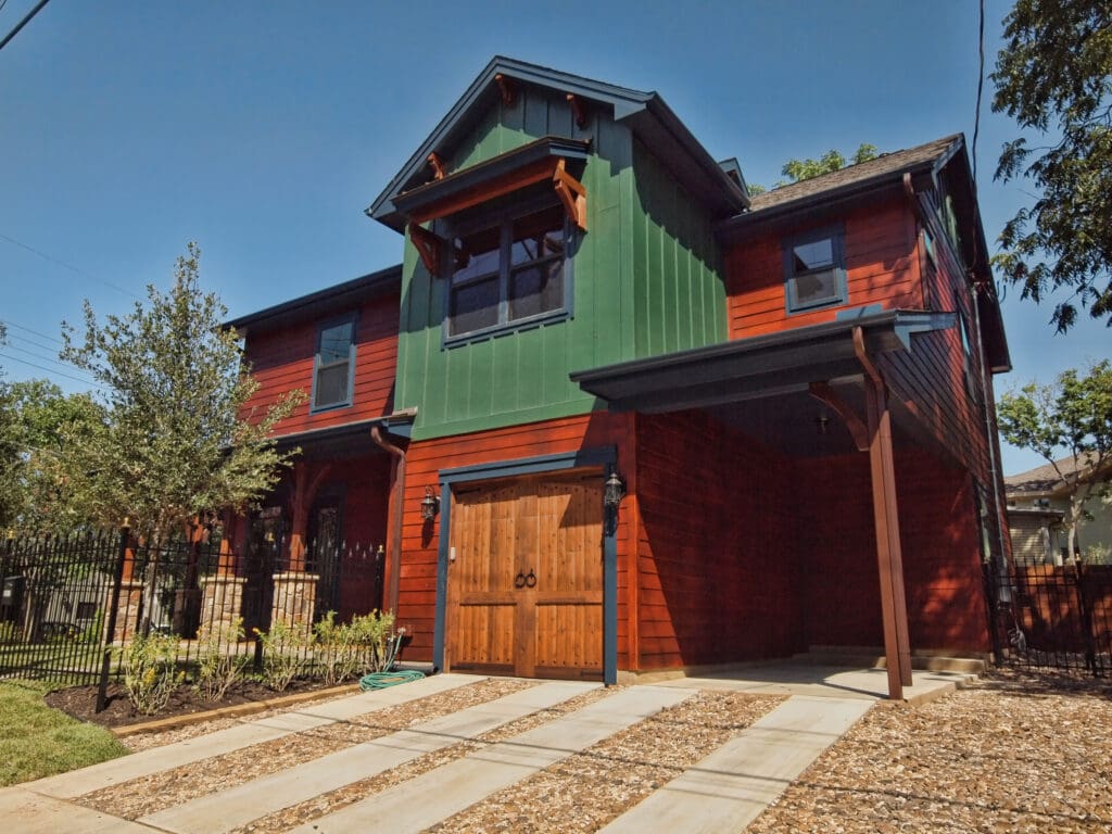 Green and red two-story house with garage.