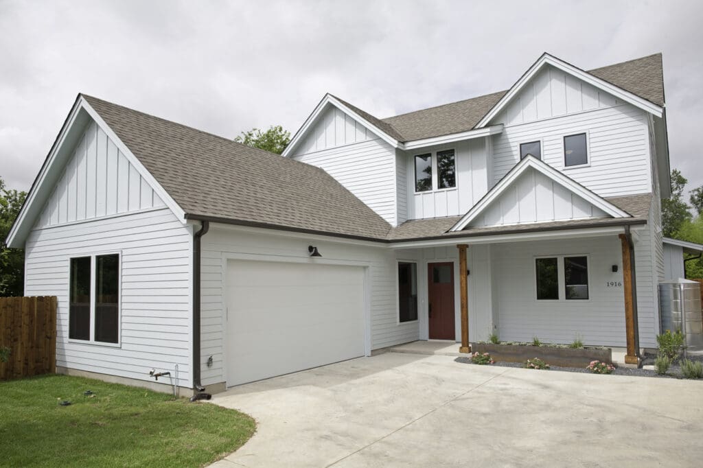 White house with garage door and porch.