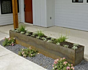 Rustic metal planter with flowers and gravel.