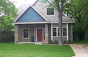 A gray and blue house with a red door.