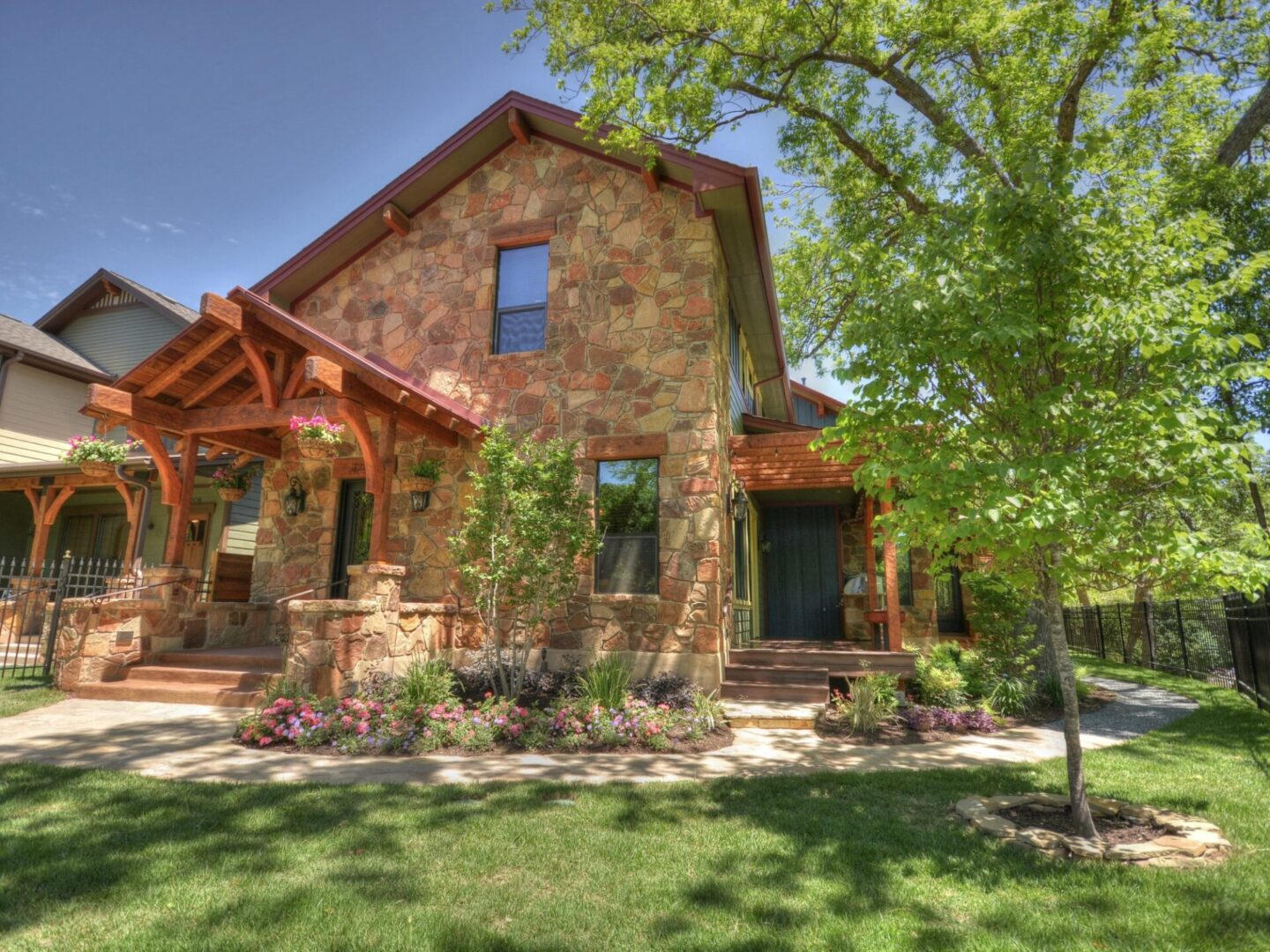 Stone house with wooden porch and landscaping.