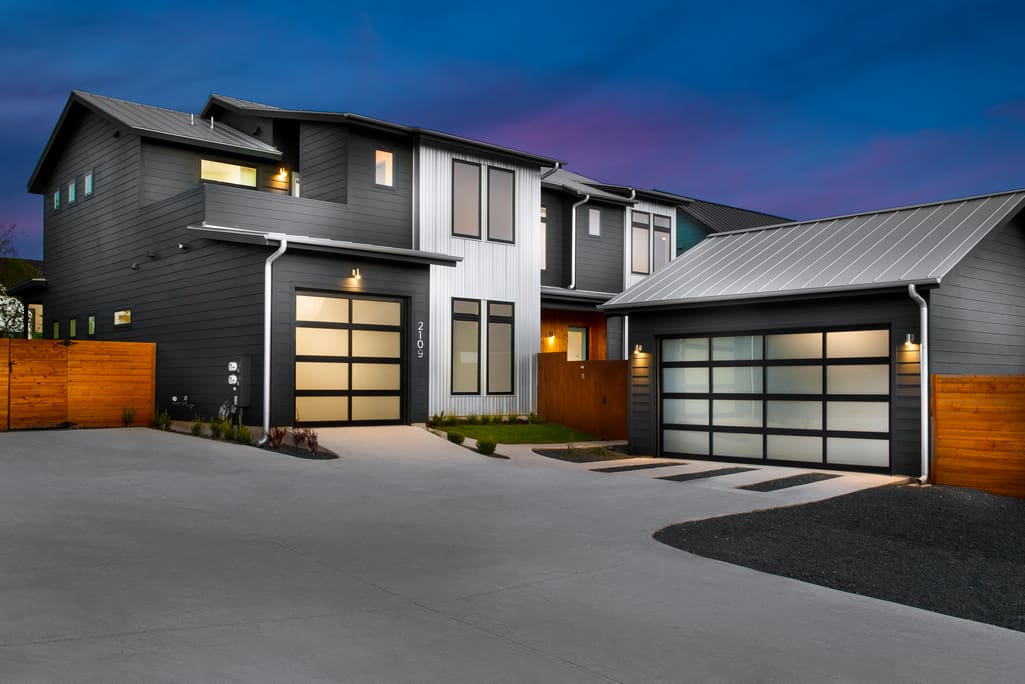 Modern home with two garage doors at dusk.