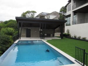 Swimming pool with patio and house in background.