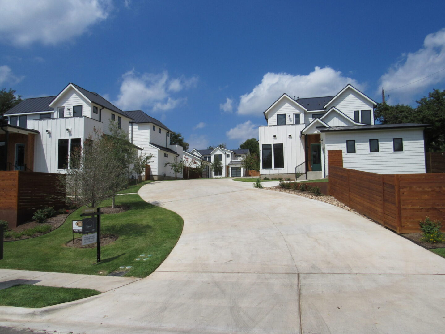 Modern white houses with driveway and fence.