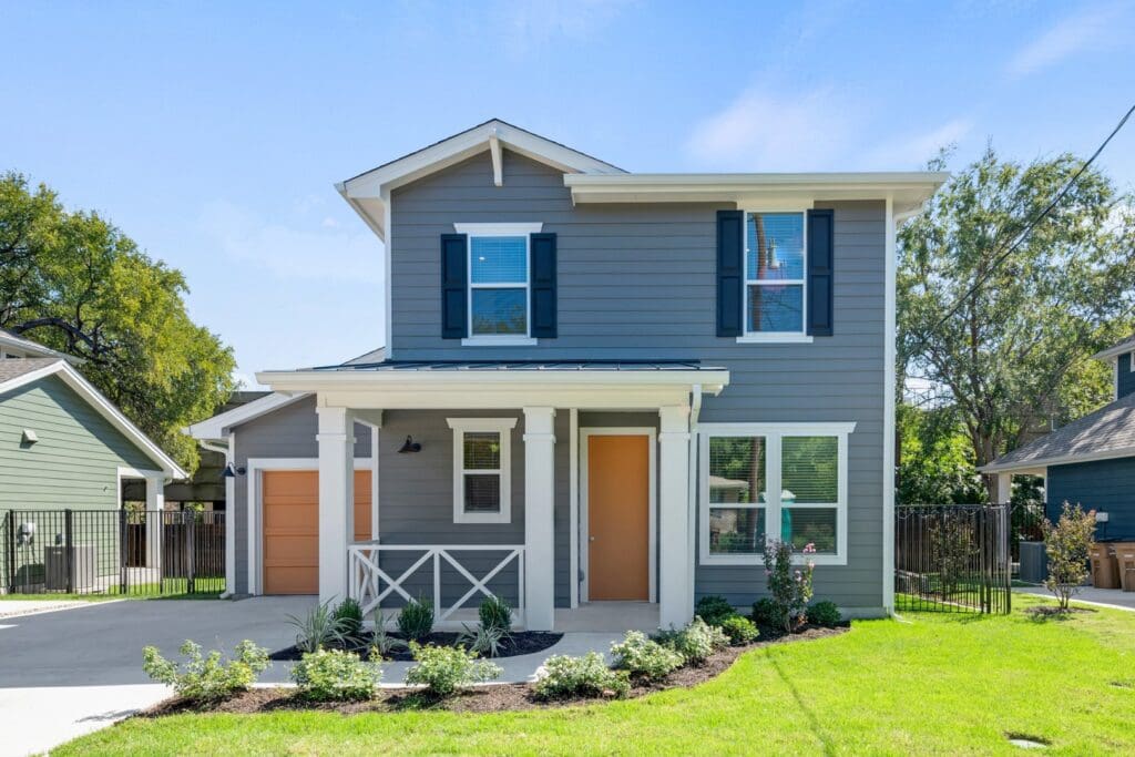 Gray house with orange door and porch.